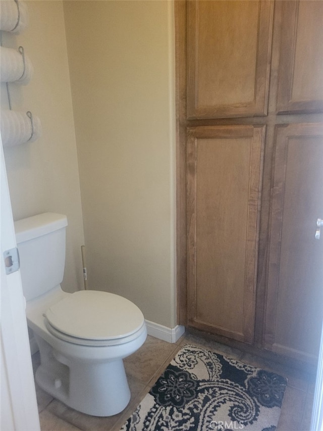 bathroom with toilet, baseboards, and tile patterned floors