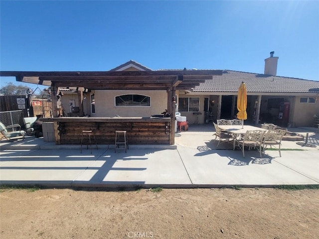 rear view of property with a chimney, a patio, stucco siding, and a tile roof