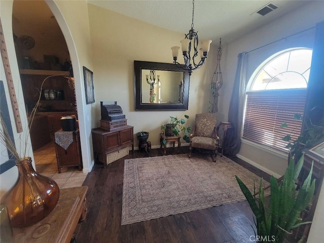 living area with a chandelier, arched walkways, wood finished floors, and baseboards