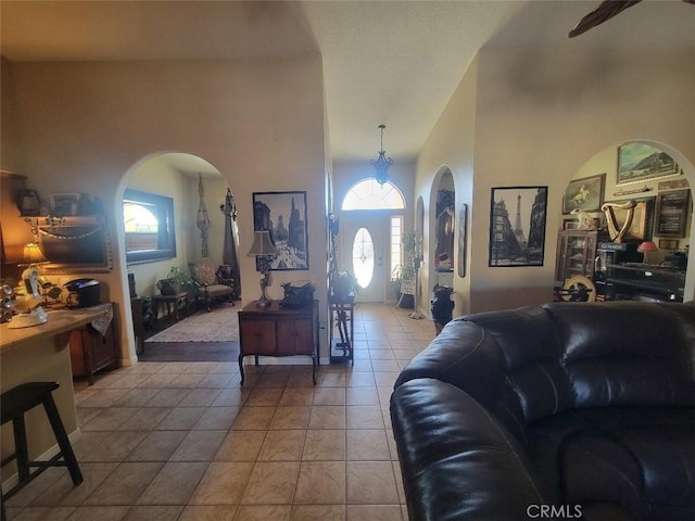 living room featuring light tile patterned flooring, arched walkways, and a towering ceiling