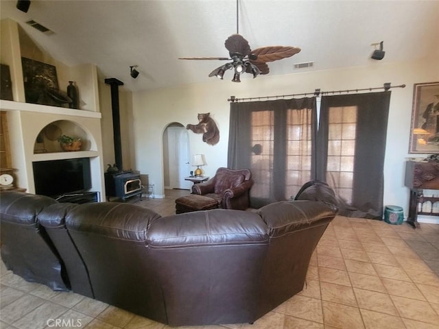 living area featuring a wood stove, built in shelves, a ceiling fan, and light tile patterned floors