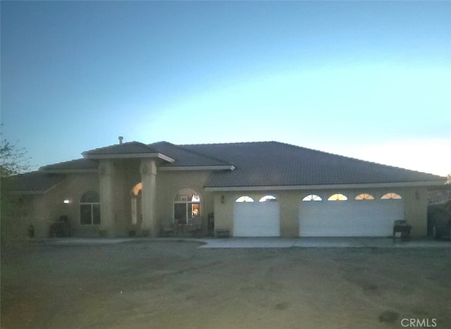 view of front of home featuring dirt driveway and a garage