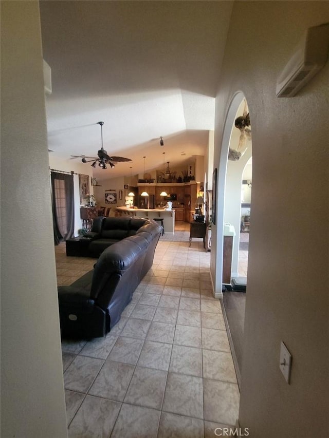 living room with lofted ceiling, ceiling fan, and arched walkways