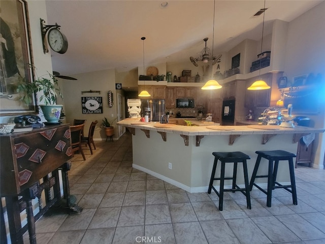 kitchen with tile countertops, black microwave, fridge, stainless steel refrigerator with ice dispenser, and decorative backsplash