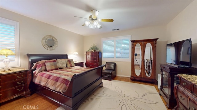 bedroom with light wood-style floors, visible vents, and ceiling fan