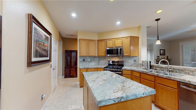 kitchen featuring light stone countertops, a kitchen island, a sink, appliances with stainless steel finishes, and tasteful backsplash