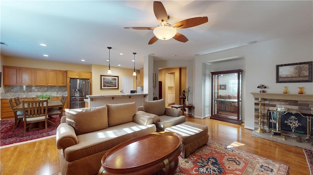 living room featuring recessed lighting, light wood-style floors, a fireplace, baseboards, and ceiling fan