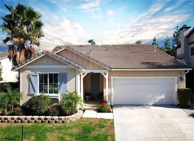 ranch-style house featuring a front lawn, a tiled roof, a garage, and driveway