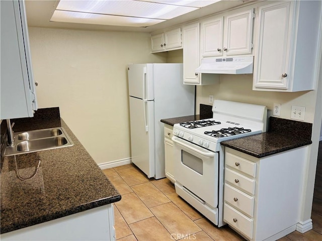 kitchen with a sink, dark countertops, under cabinet range hood, and white appliances