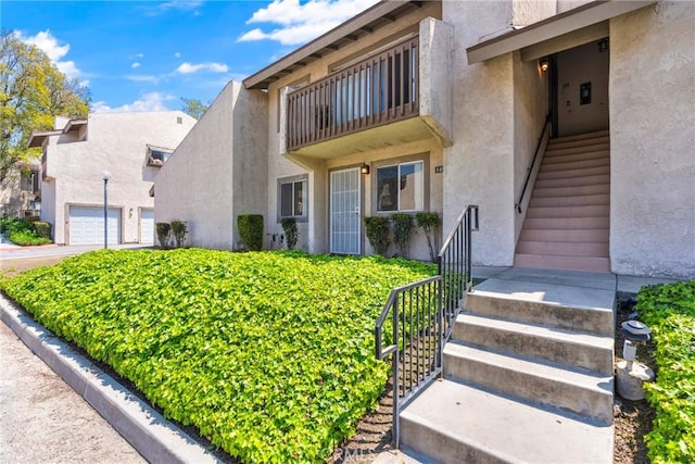 1251 S Meadow Ln Unit 145, Colton, CA 92324 - view of front facade featuring stucco siding, stairway, and a garage