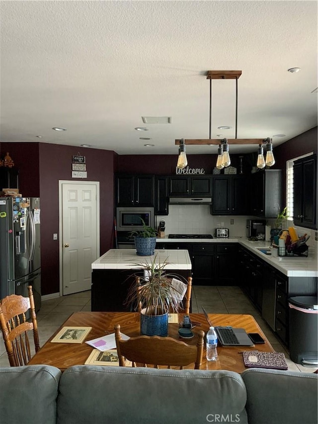 5230 Starling St, Fontana, CA 92336 - kitchen with light tile patterned floors, light countertops, dark cabinetry, and appliances with stainless steel finishes