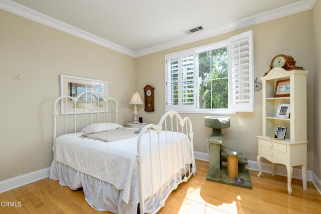 bedroom with baseboards, visible vents, ornamental molding, and wood finished floors