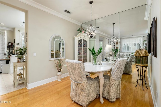 dining area featuring crown molding, light wood-style flooring, baseboards, visible vents, and an inviting chandelier