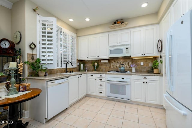 kitchen featuring backsplash, light tile patterned floors, and white appliances