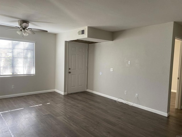 spare room with ceiling fan, visible vents, baseboards, and dark wood-style floors