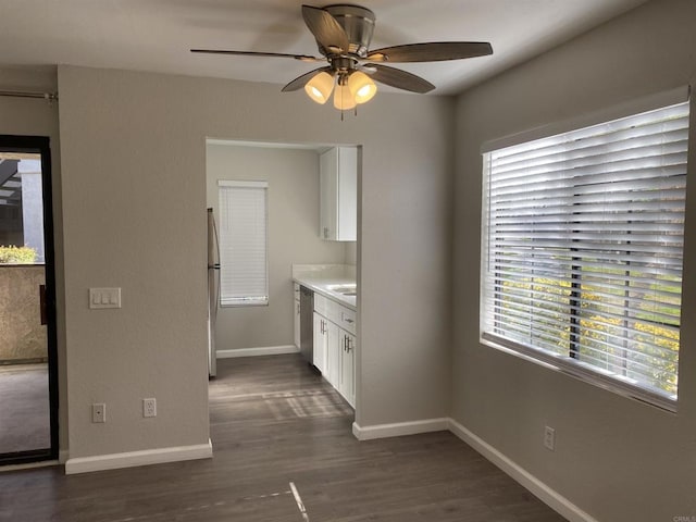 unfurnished dining area featuring baseboards, dark wood finished floors, and a ceiling fan