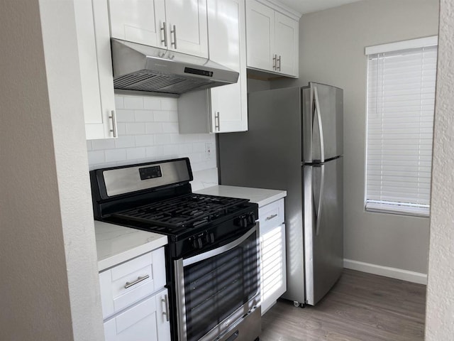 kitchen with baseboards, under cabinet range hood, white cabinets, gas stove, and dark wood-style flooring