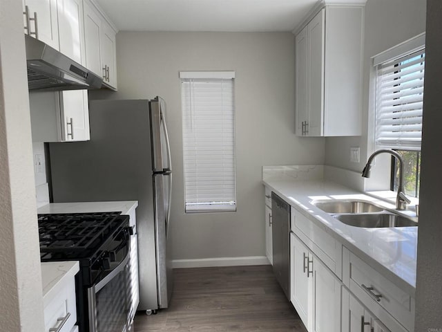 kitchen featuring dark wood-style floors, black gas stove, a sink, under cabinet range hood, and stainless steel dishwasher