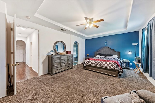 28183 Rocky Cove Dr, Menifee, CA 92585 - carpeted bedroom featuring arched walkways, a tray ceiling, and ceiling fan