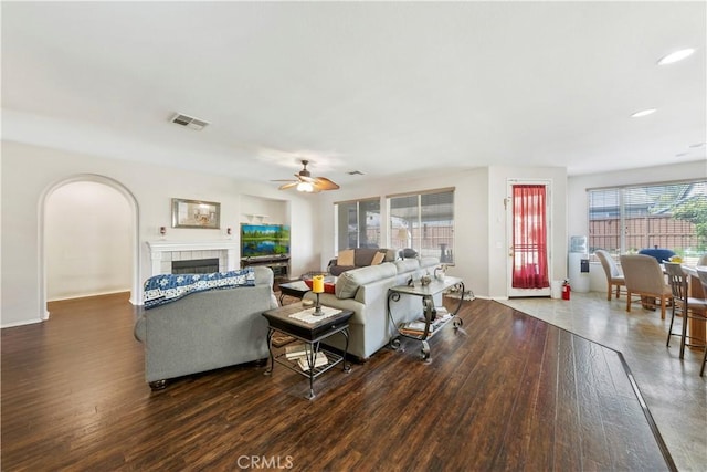 28183 Rocky Cove Dr, Menifee, CA 92585 - living area featuring wood finished floors, ceiling fan, a tiled fireplace, arched walkways, and recessed lighting
