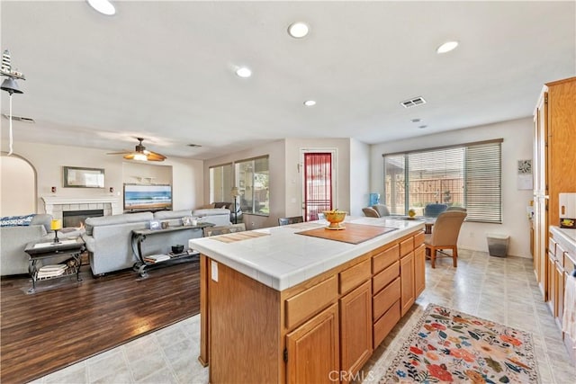 28183 Rocky Cove Dr, Menifee, CA 92585 - kitchen featuring tile counters, ceiling fan, a tile fireplace, a center island, and recessed lighting