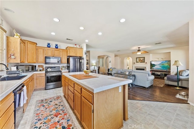 28183 Rocky Cove Dr, Menifee, CA 92585 - kitchen with stainless steel appliances, tile counters, arched walkways, ceiling fan, and a center island