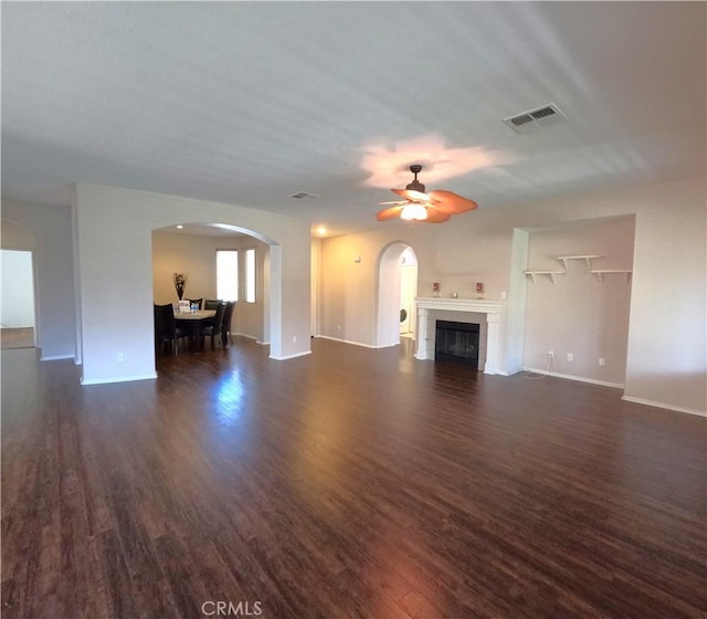 28183 Rocky Cove Dr, Menifee, CA 92585 - unfurnished living room featuring arched walkways, dark wood finished floors, ceiling fan, and a fireplace