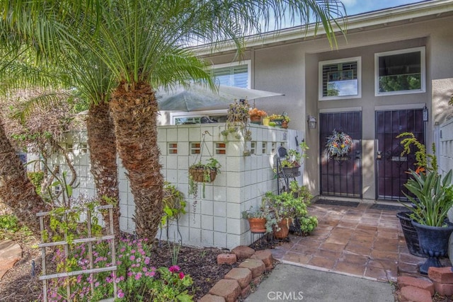 doorway to property with stucco siding and fence