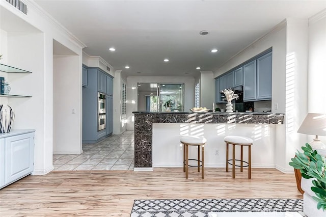 2768 Somerset Pl, Rowland Heights, CA 91748 - kitchen with light wood-style floors, a breakfast bar area, a peninsula, visible vents, and ornamental molding