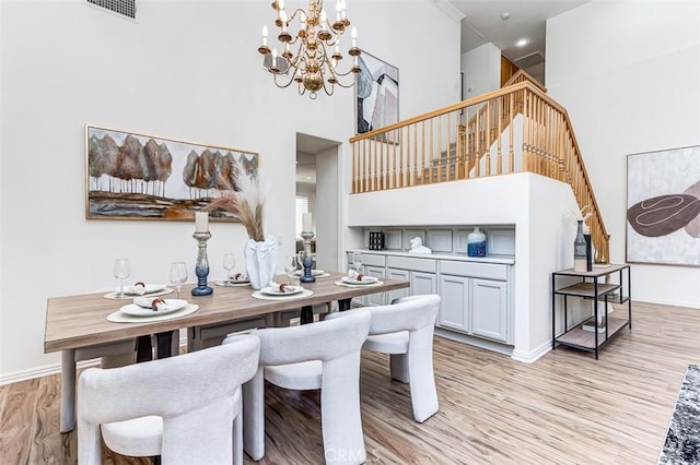 2768 Somerset Pl, Rowland Heights, CA 91748 - dining area featuring stairs, a towering ceiling, baseboards, a chandelier, and light wood-style flooring
