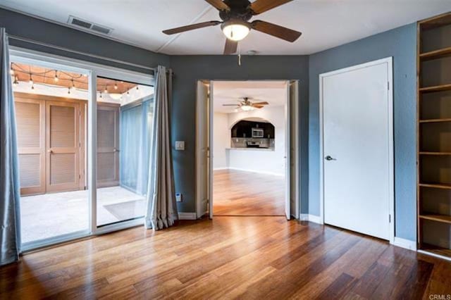 spare room featuring visible vents, baseboards, ceiling fan, and wood finished floors