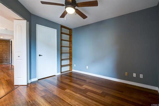 unfurnished bedroom featuring wood finished floors, baseboards, a closet, and ceiling fan