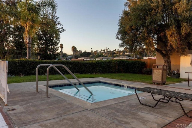 pool at dusk with a patio and fence