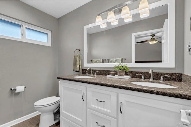 bathroom with a sink, toilet, wood finished floors, and double vanity