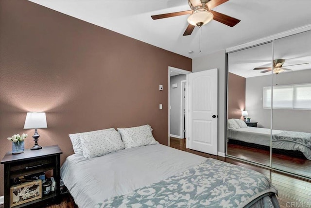 bedroom featuring baseboards, wood finished floors, a closet, and ceiling fan