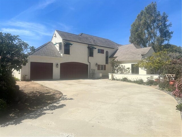 view of front of house featuring stucco siding, a garage, driveway, and a tiled roof