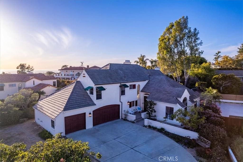 view of front facade featuring a tile roof, a garage, driveway, and stucco siding