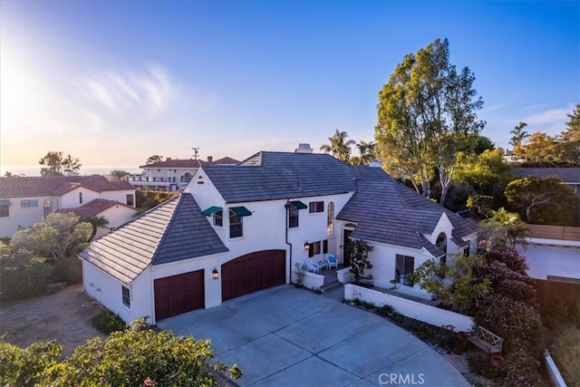 view of front facade featuring a tile roof, a garage, driveway, and stucco siding