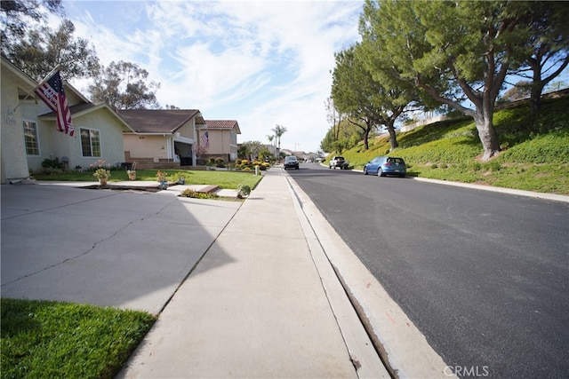view of road with a residential view, sidewalks, and curbs