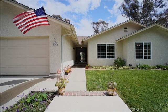 view of front of property featuring stucco siding, a front yard, and an attached garage