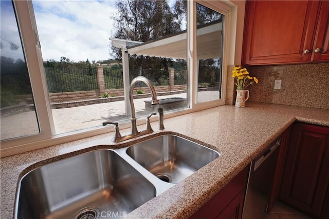 kitchen with light stone countertops, decorative backsplash, dishwasher, and a sink
