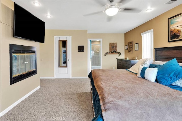 carpeted bedroom with a glass covered fireplace, visible vents, a ceiling fan, and baseboards