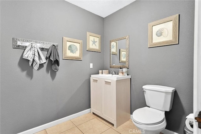 half bath with baseboards, toilet, vanity, and tile patterned flooring