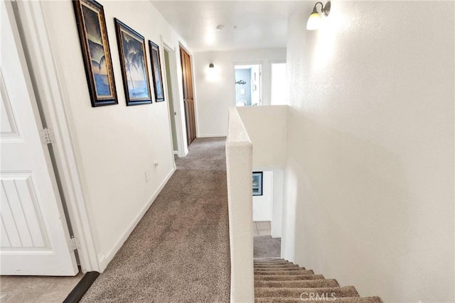 corridor featuring an upstairs landing, baseboards, and carpet