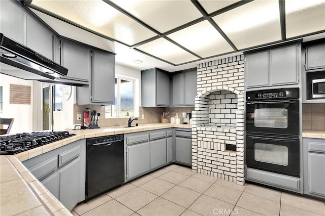 kitchen with black appliances, gray cabinets, tasteful backsplash, tile countertops, and light tile patterned floors