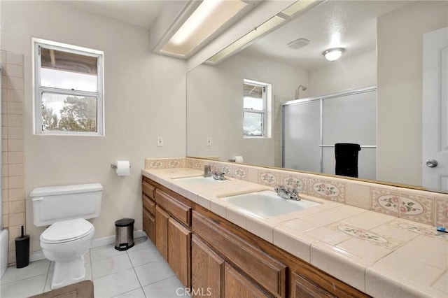 bathroom featuring a shower with door, toilet, and a sink