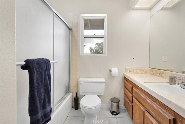 bathroom with vanity, baseboards, shower / bath combination with glass door, tile patterned flooring, and toilet