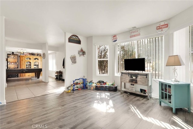 living room with wood finished floors, visible vents, and a healthy amount of sunlight