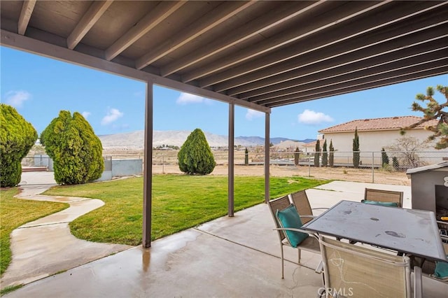 view of patio featuring a mountain view, outdoor dining area, and a fenced backyard