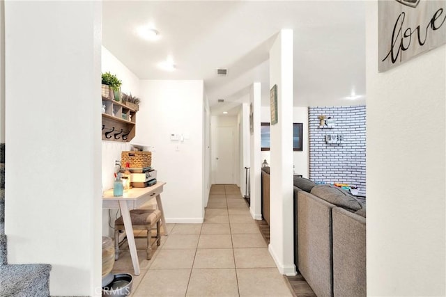 hall with light tile patterned flooring, visible vents, and baseboards